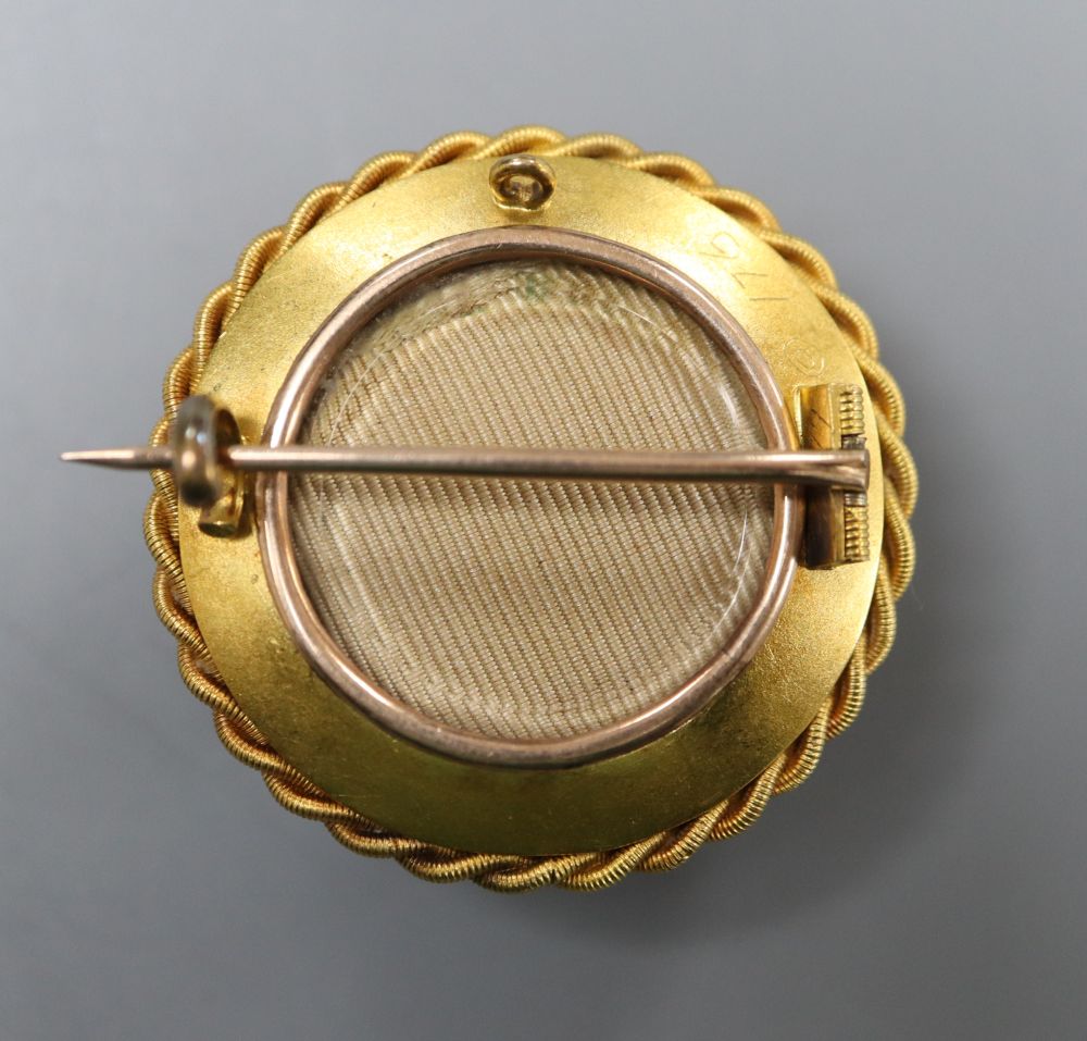 A Victorian yellow metal and Essex crystal set circular brooch, decorated with the head of a cat, with ropetwist border,